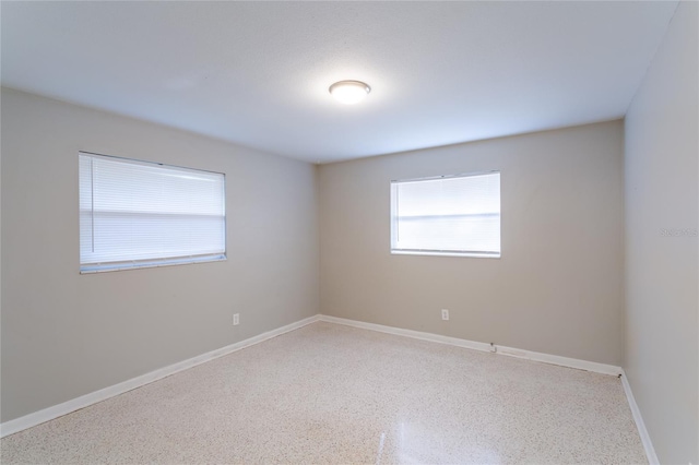 empty room featuring speckled floor and baseboards