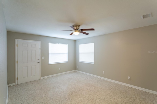 empty room with ceiling fan, visible vents, and baseboards