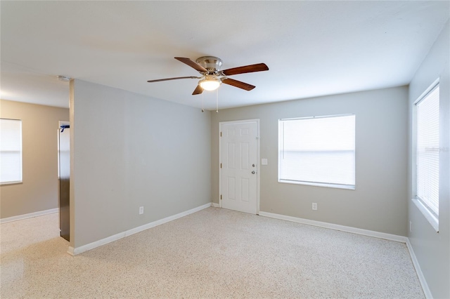 spare room with a ceiling fan and baseboards