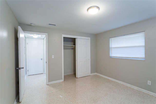 unfurnished bedroom featuring speckled floor, a closet, visible vents, and baseboards