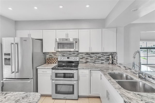 kitchen featuring stainless steel appliances, white cabinets, a sink, and backsplash