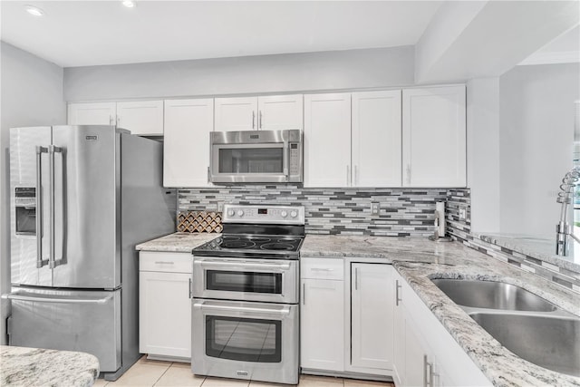 kitchen with light stone counters, stainless steel appliances, backsplash, white cabinetry, and a sink