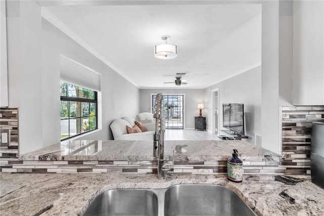 kitchen featuring open floor plan, crown molding, and light stone countertops