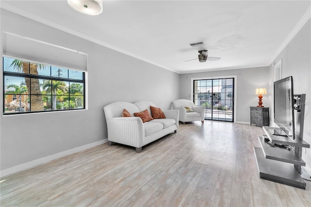 living room with baseboards, light wood-style floors, a ceiling fan, and crown molding