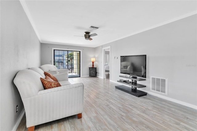 living area featuring baseboards, light wood-style floors, visible vents, and crown molding