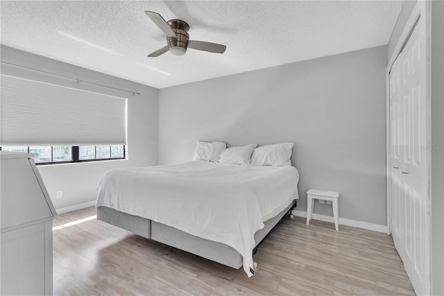 bedroom with light wood-style floors, a ceiling fan, baseboards, and a textured ceiling