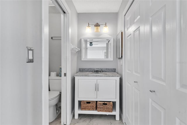 bathroom featuring marble finish floor, vanity, toilet, and a textured ceiling