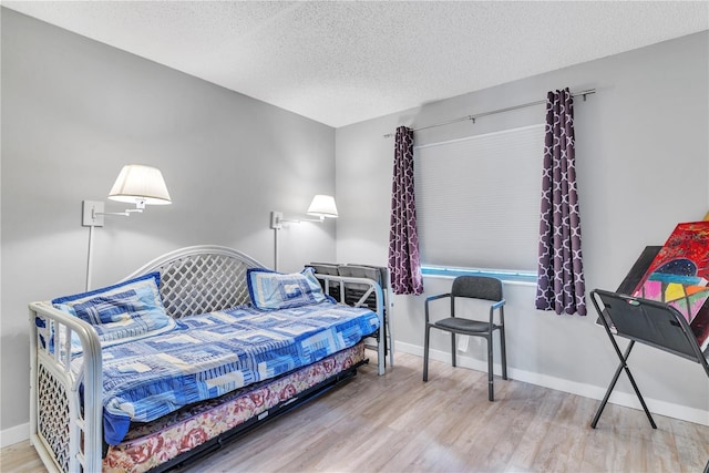 bedroom with a textured ceiling, baseboards, and wood finished floors