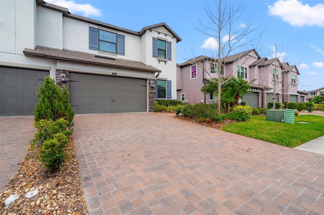 view of property with a garage, stone siding, decorative driveway, and stucco siding