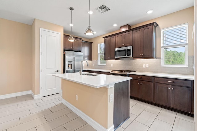 kitchen featuring dark brown cabinetry, a sink, visible vents, appliances with stainless steel finishes, and backsplash