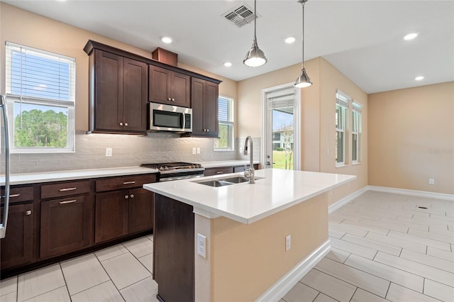 kitchen with a center island with sink, visible vents, appliances with stainless steel finishes, a sink, and backsplash