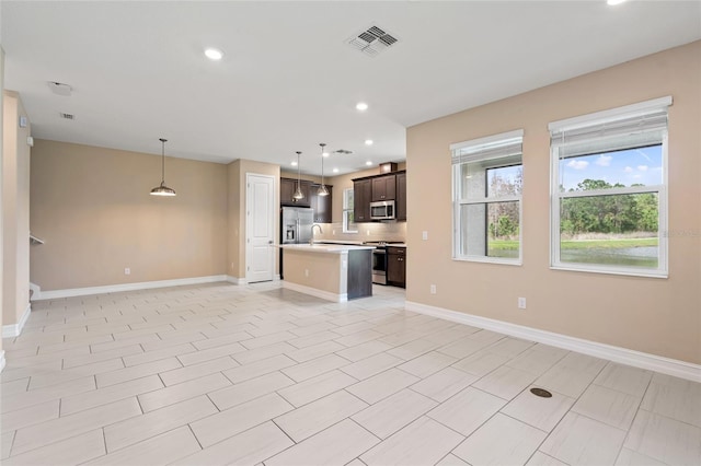 kitchen with a center island with sink, stainless steel appliances, light countertops, visible vents, and open floor plan