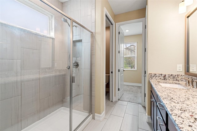 full bathroom with a shower stall, baseboards, and vanity