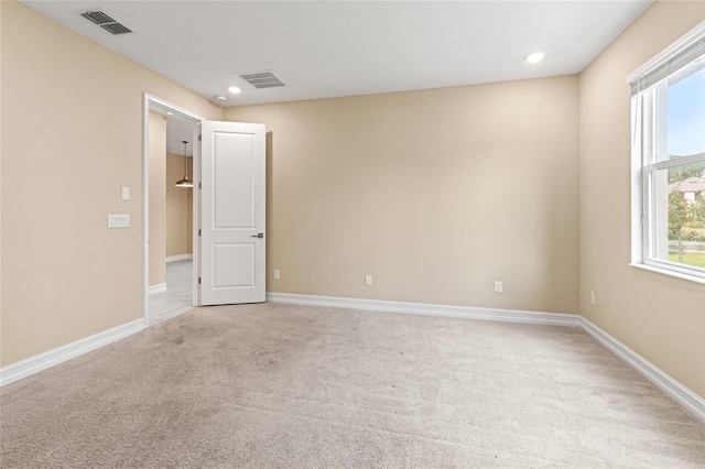 unfurnished room with baseboards, visible vents, and light colored carpet