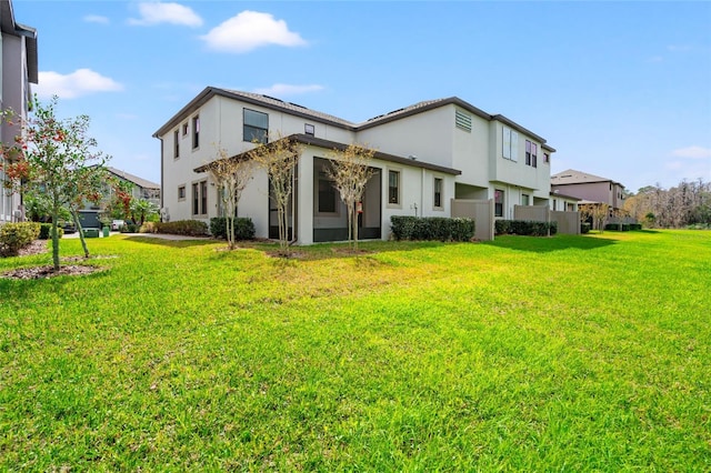 rear view of house with a lawn and stucco siding