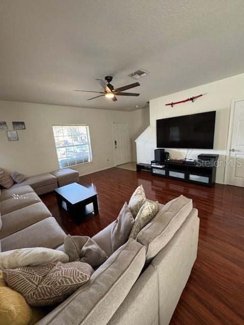 living room featuring a ceiling fan, visible vents, and wood finished floors