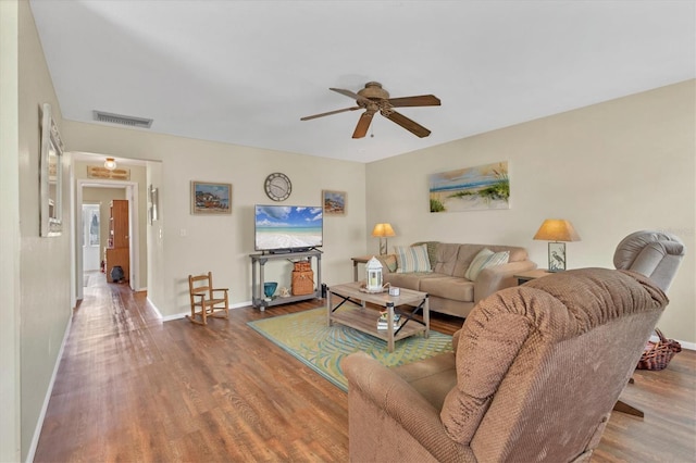 living room featuring ceiling fan, wood finished floors, visible vents, and baseboards