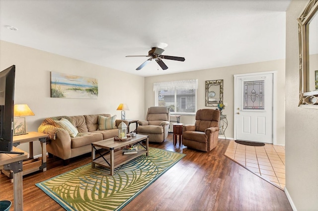 living area featuring baseboards, ceiling fan, and wood finished floors