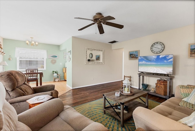 living area with visible vents, baseboards, wood finished floors, and ceiling fan with notable chandelier