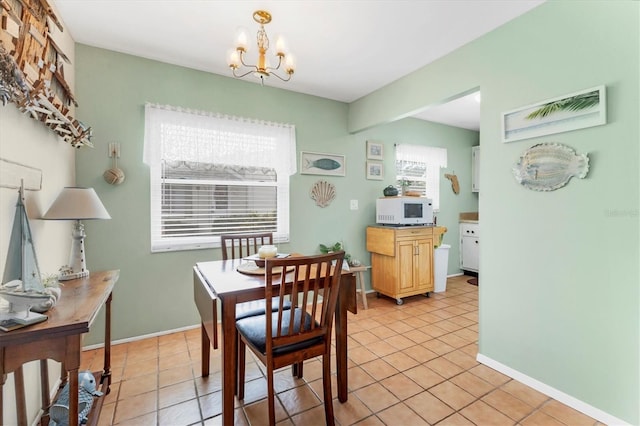 dining space featuring light tile patterned floors, baseboards, and an inviting chandelier