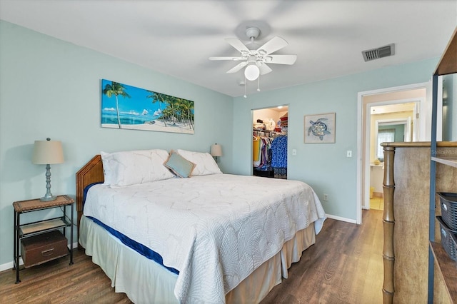 bedroom with wood finished floors, visible vents, baseboards, a closet, and a walk in closet