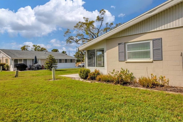 view of side of home with a lawn and concrete block siding