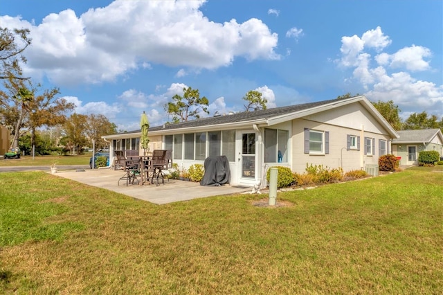 rear view of property with a sunroom, a lawn, and a patio area