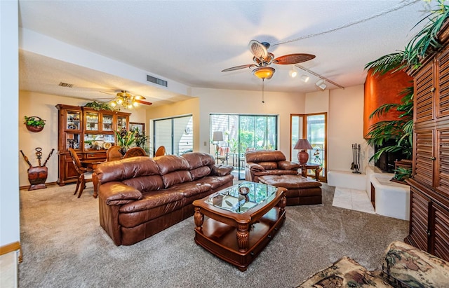 living room featuring rail lighting, visible vents, a ceiling fan, and light colored carpet