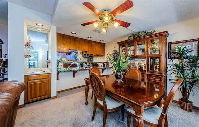 dining area with ceiling fan, a textured ceiling, light carpet, visible vents, and baseboards