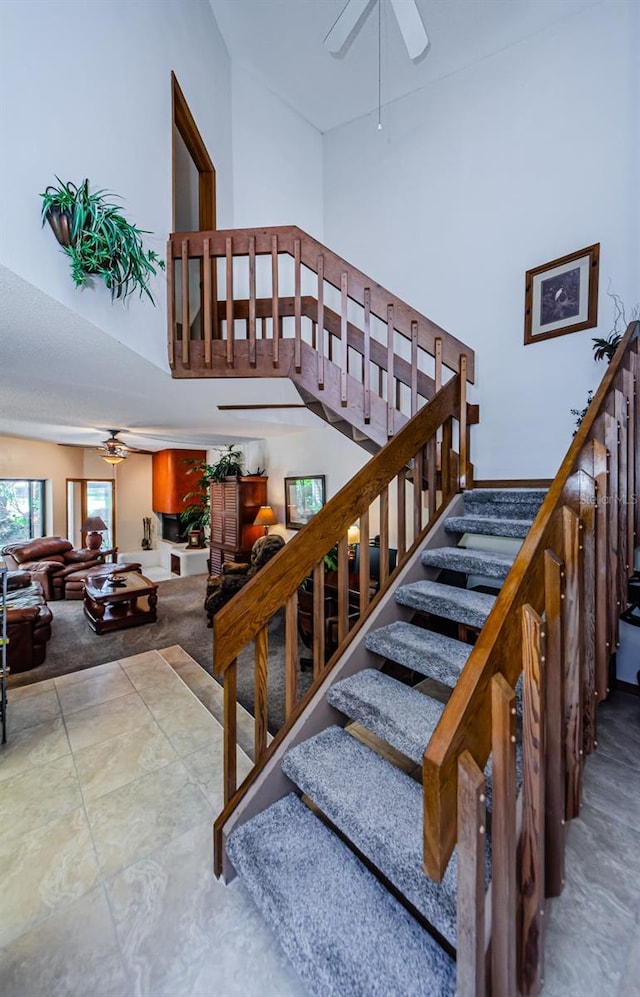 staircase with ceiling fan and high vaulted ceiling