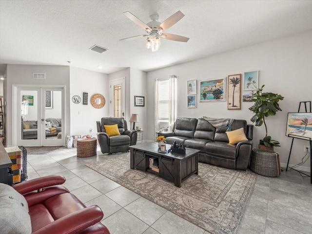 living area featuring french doors, visible vents, light tile patterned flooring, ceiling fan, and a textured ceiling