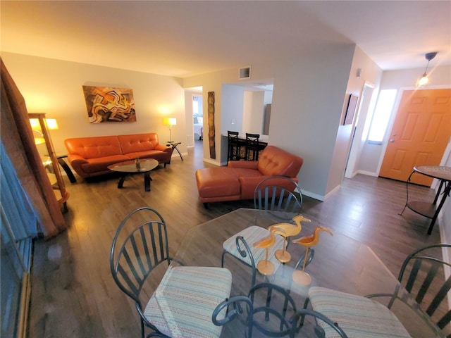 living room with wood finished floors, visible vents, and baseboards