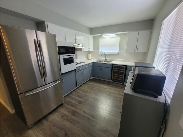 kitchen featuring dark wood-style floors, wine cooler, a sink, white appliances, and under cabinet range hood