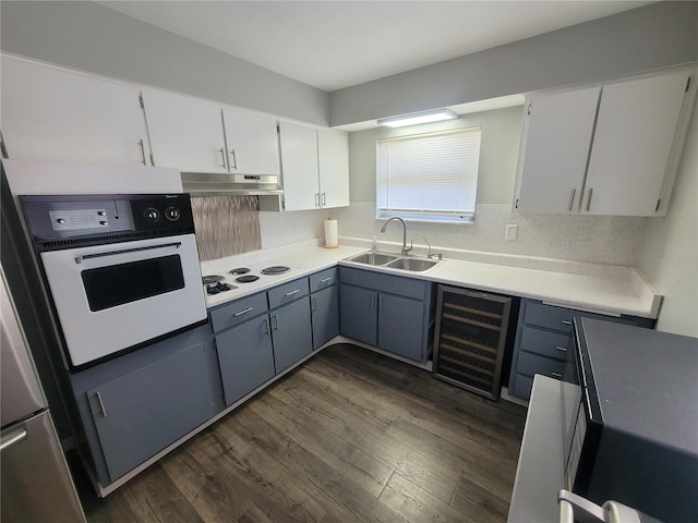 kitchen featuring dark wood-style floors, a sink, beverage cooler, white appliances, and under cabinet range hood