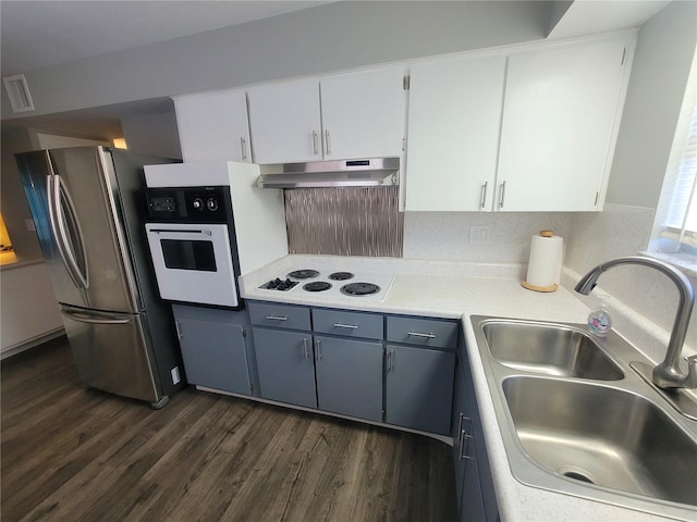 kitchen featuring white appliances, a sink, under cabinet range hood, and dark wood-style flooring