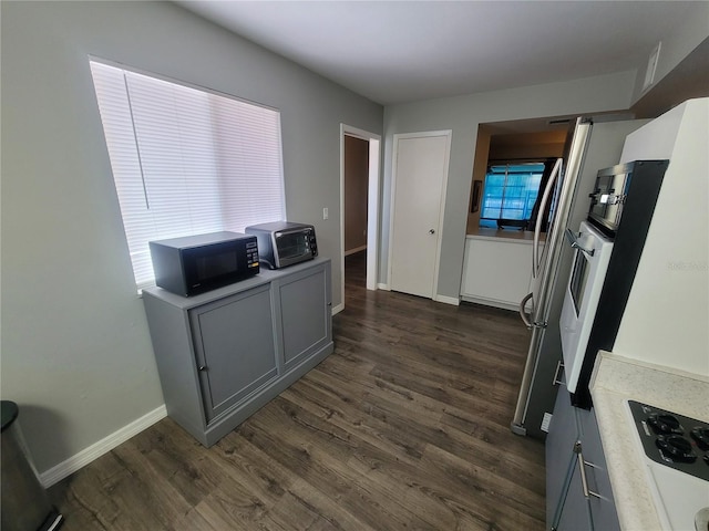 kitchen featuring black microwave, a toaster, dark wood-style flooring, baseboards, and light countertops