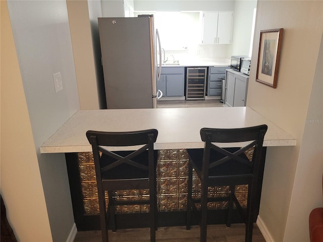 kitchen featuring wine cooler, gray cabinetry, a sink, light countertops, and freestanding refrigerator