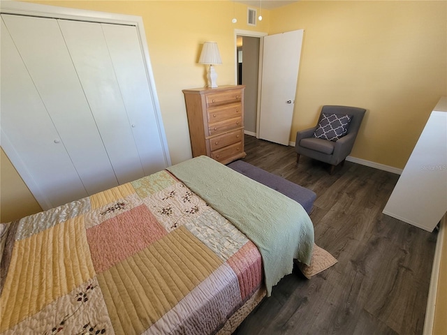 bedroom featuring a closet, wood finished floors, visible vents, and baseboards