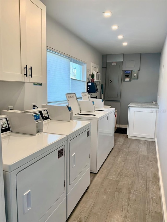 laundry area with light wood-type flooring, washing machine and dryer, cabinet space, and baseboards