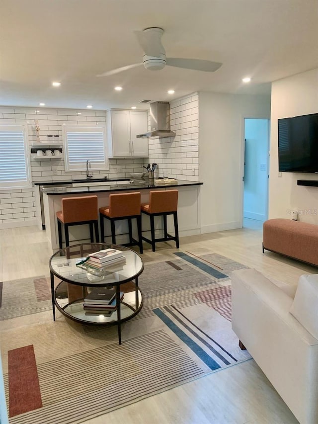 living area with light wood-style flooring, baseboards, a ceiling fan, and recessed lighting