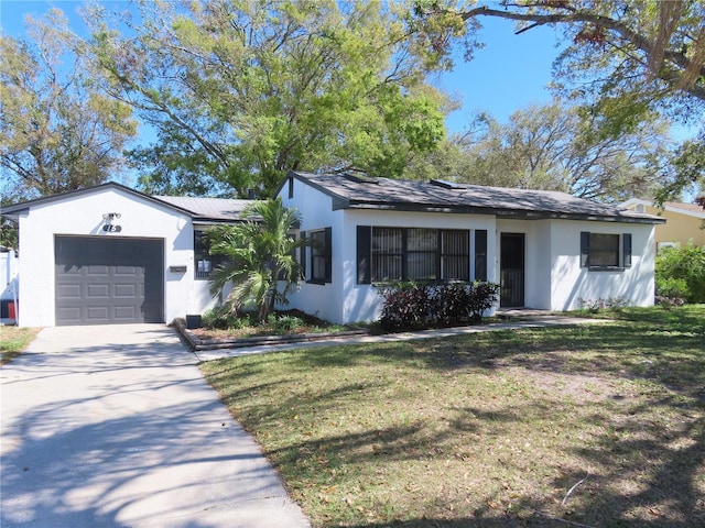 ranch-style home with a garage, a front yard, concrete driveway, and stucco siding