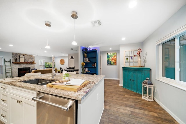 kitchen with visible vents, dark wood finished floors, dishwasher, open floor plan, and a stone fireplace