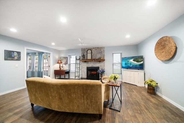 living area featuring recessed lighting, baseboards, dark wood finished floors, and a stone fireplace