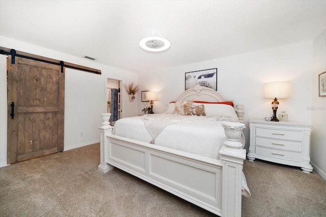 bedroom featuring carpet floors, a barn door, visible vents, and baseboards