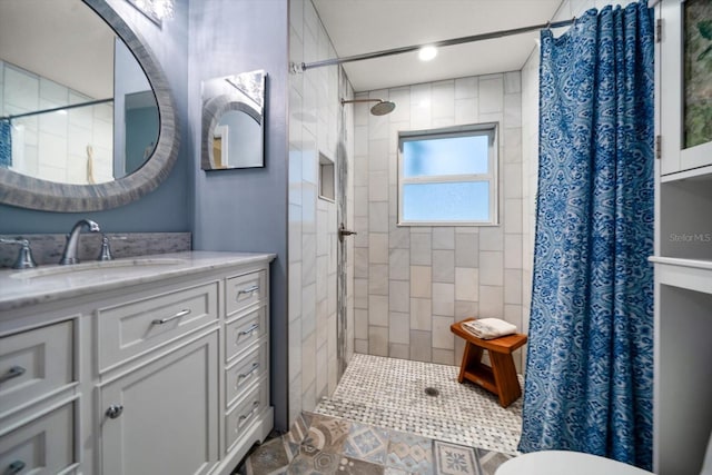 bathroom with tiled shower and vanity