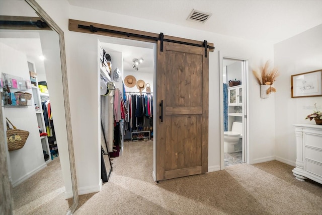 interior space with carpet floors, visible vents, and a barn door