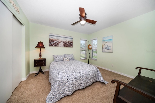 carpeted bedroom with ceiling fan, a closet, and baseboards