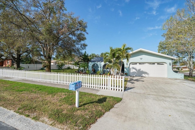 view of front facade with a fenced front yard, a garage, driveway, stucco siding, and a front lawn