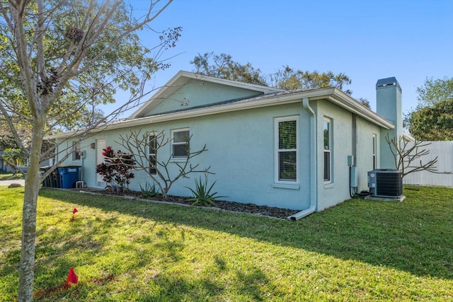 view of home's exterior with a yard, a chimney, cooling unit, and stucco siding