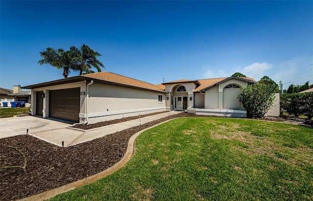 view of front of property with stucco siding, a front lawn, a garage, and driveway